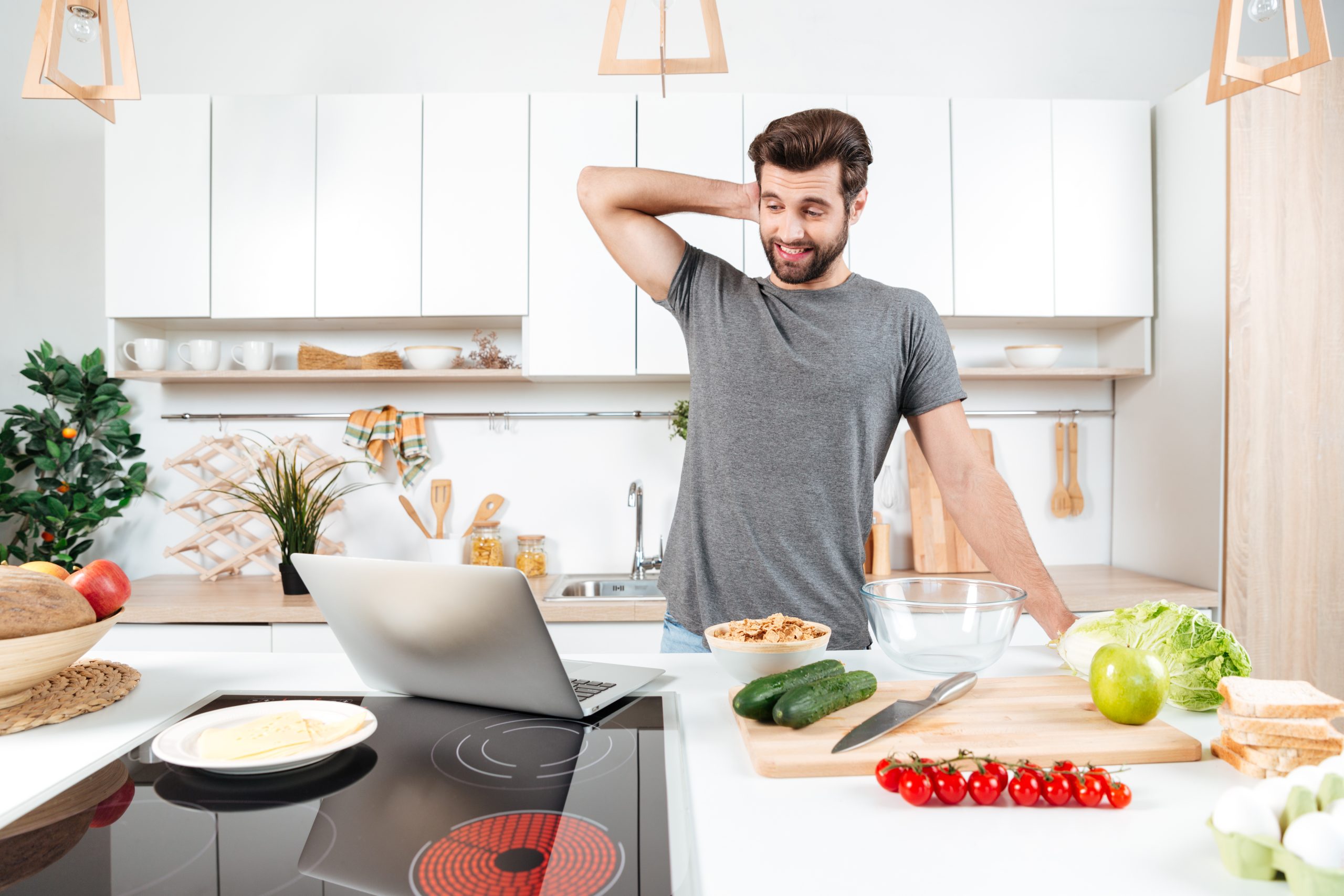 Confused handsome man cooking vegetable salad in kitchen
